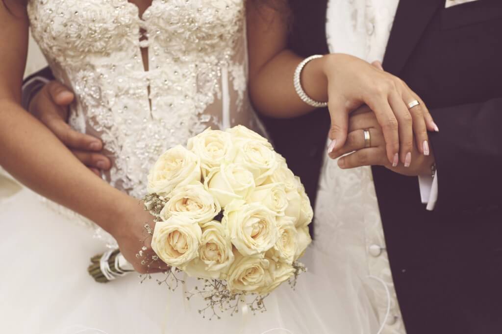 Detail of bride's roses bouquet and hands holding
