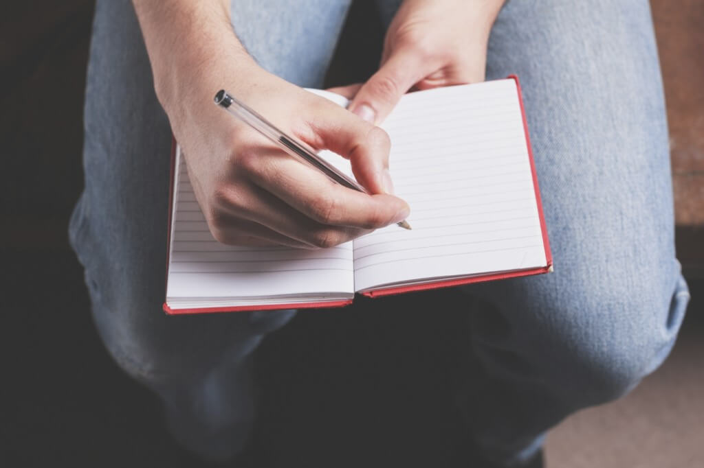 A man is taking notes in a notebook