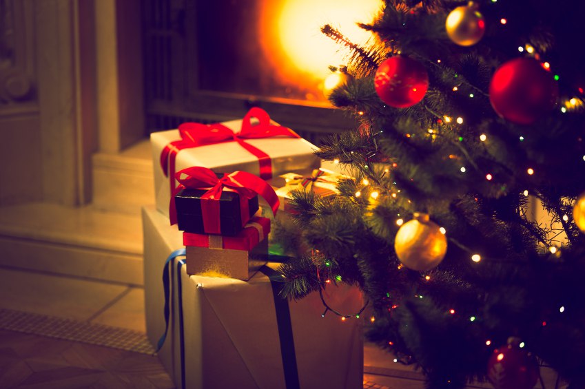 Toned photo of Christmas tree and gift boxes against burning fir