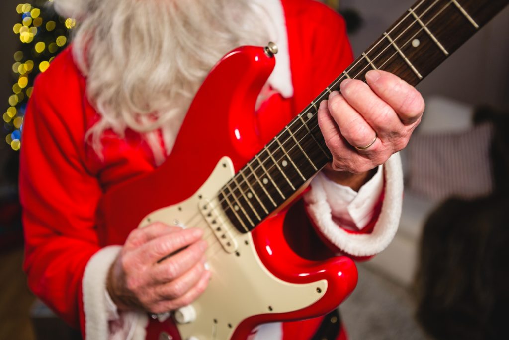 Mid-section of santa claus playing a guitar during Christmas time at home